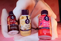 three bottles of shampoo sitting on top of a bed