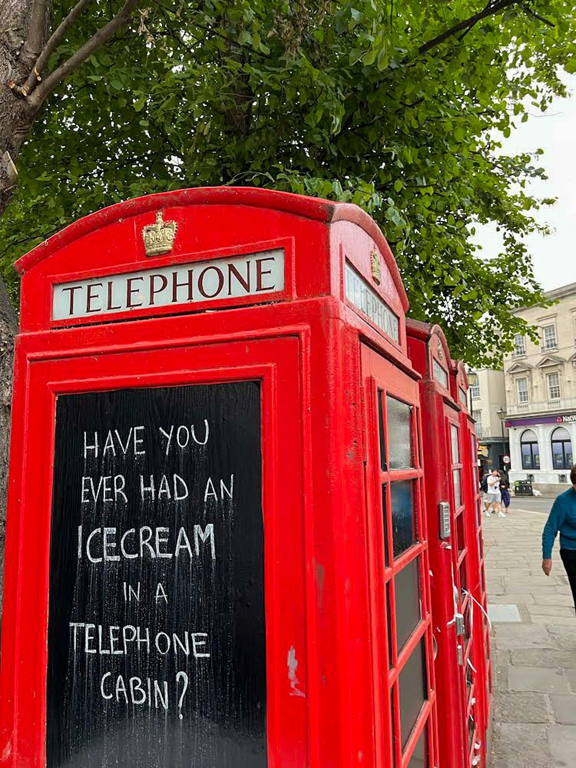 a red telephone booth sitting on the side of a road