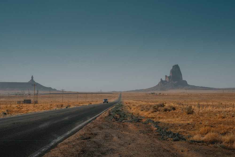 a car driving down a road in the middle of the desert