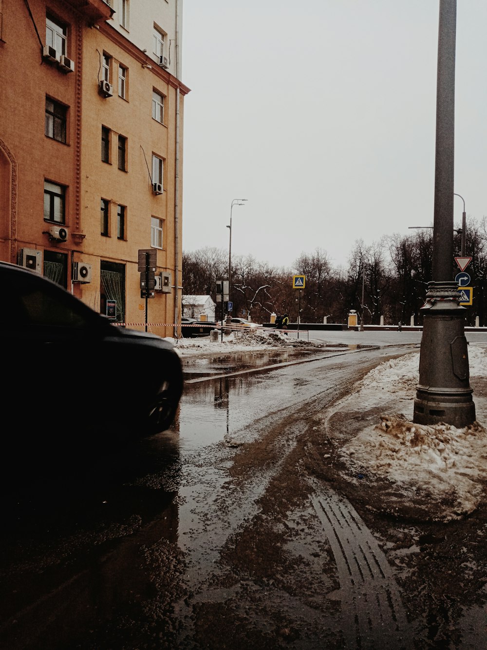 a wet street with cars parked on the side of it