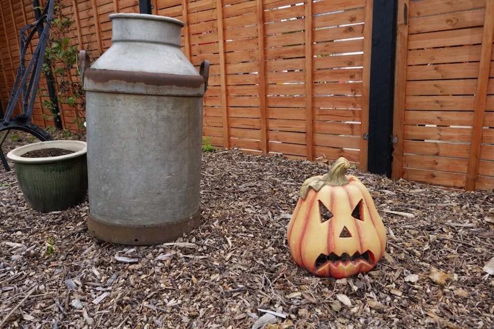 a pumpkin sitting on the ground in front of a fence