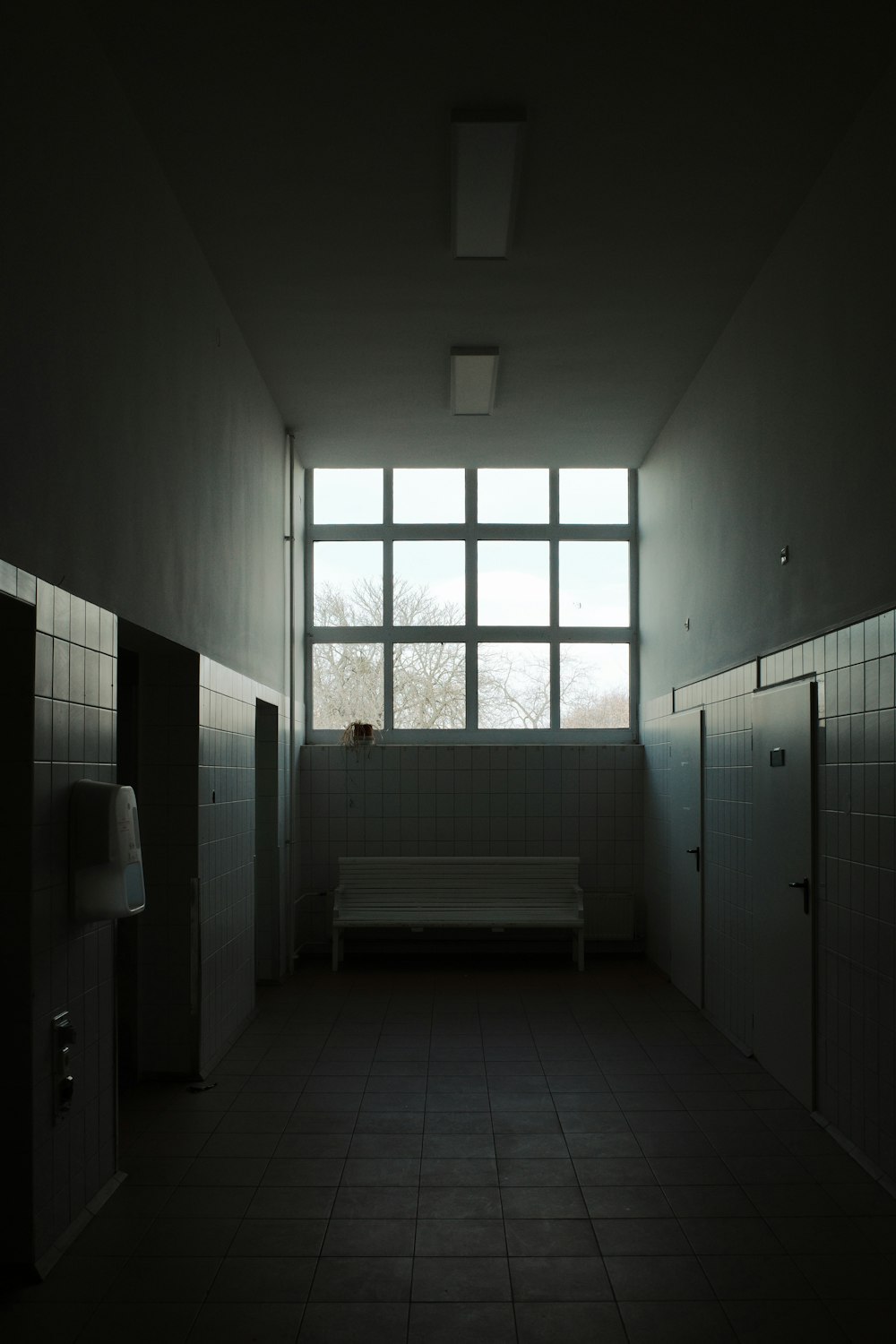a dimly lit room with a bench and urinals