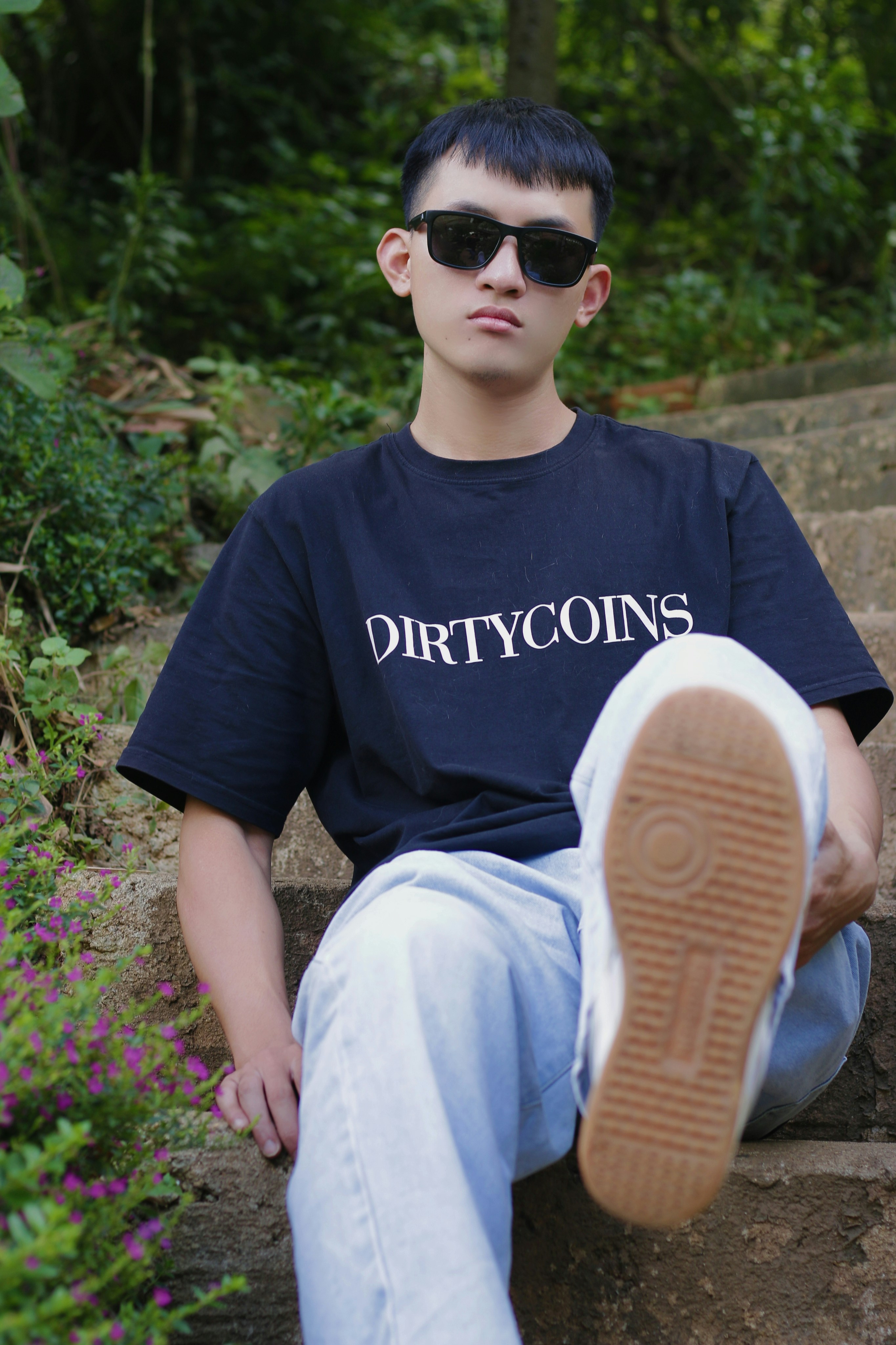 a young man wearing sunglasses sitting on a rock