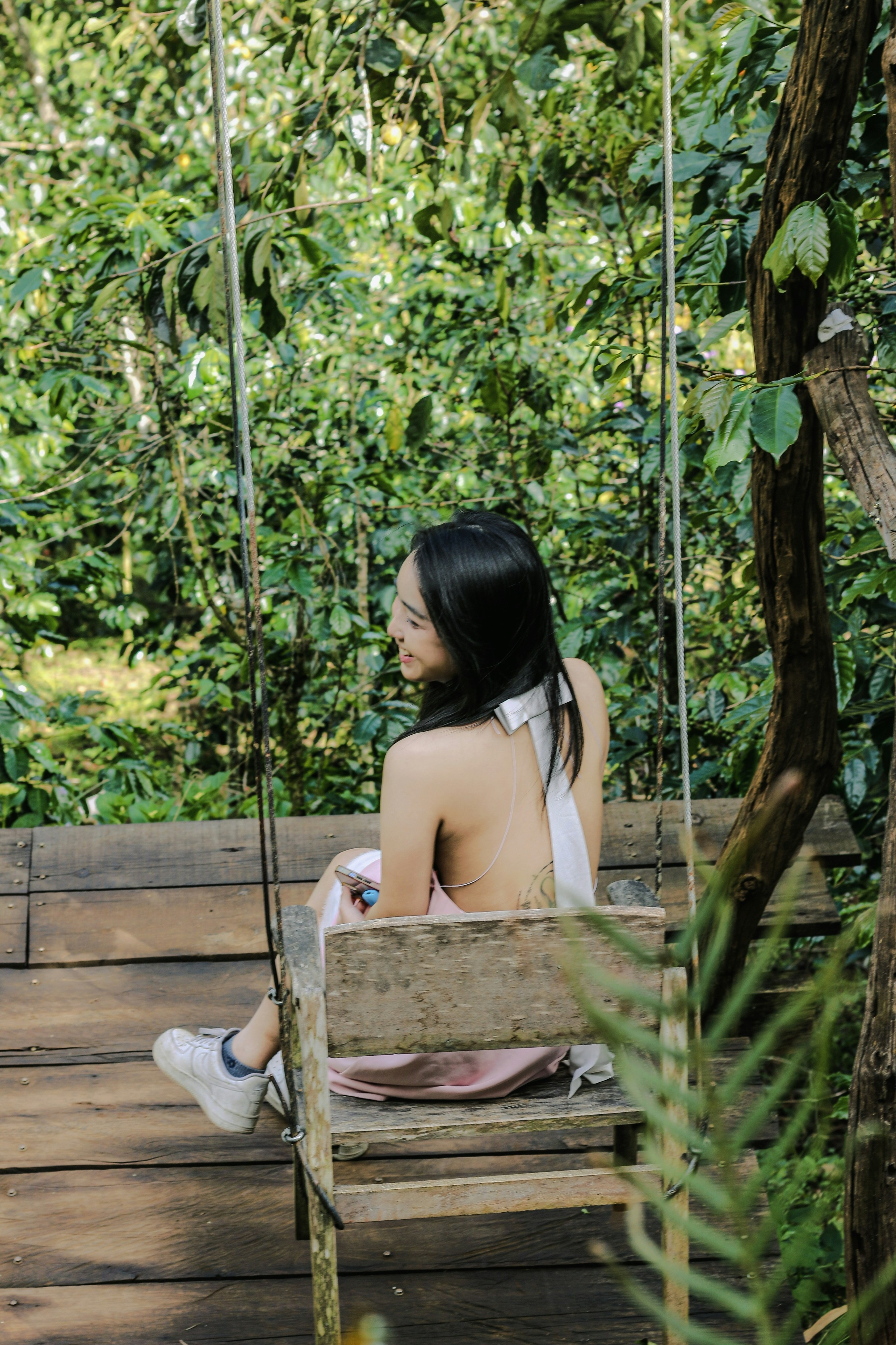 a woman sitting on a swing in the woods