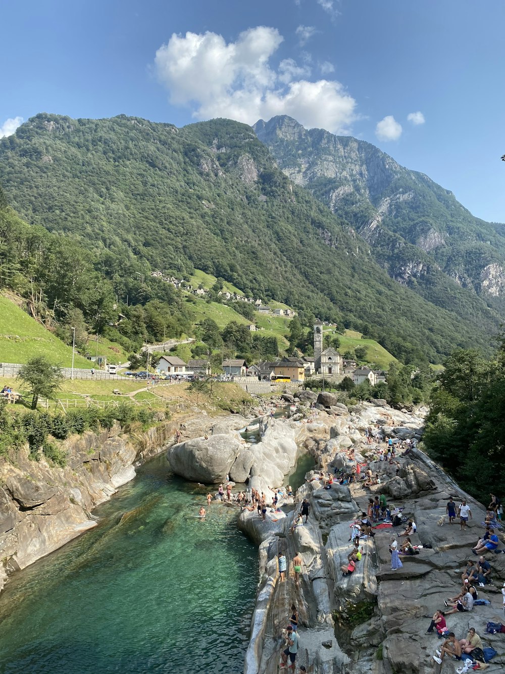 a group of people standing on top of a cliff next to a river