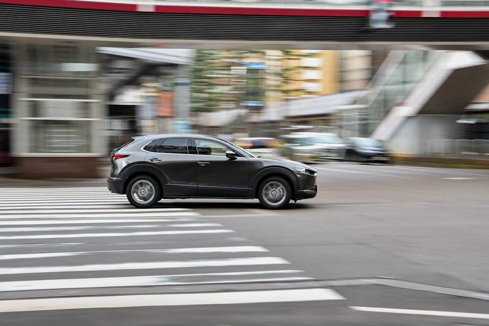 a black car driving down a street next to a tall building