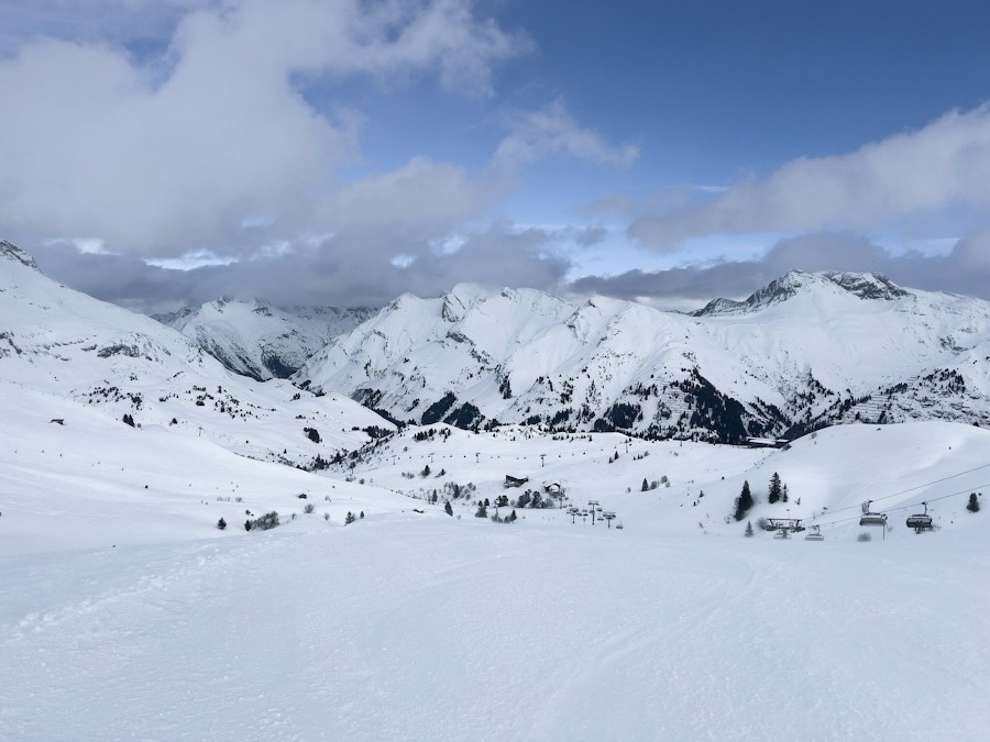 Domaine skiable enneigé des Alpes vu depuis une piste, avec des chalets au pied de sommets blancs, en illustration des vacances au ski de l’hiver 2026-2027