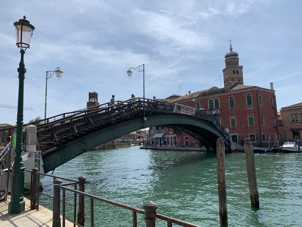 a bridge over a body of water with a clock tower in the background