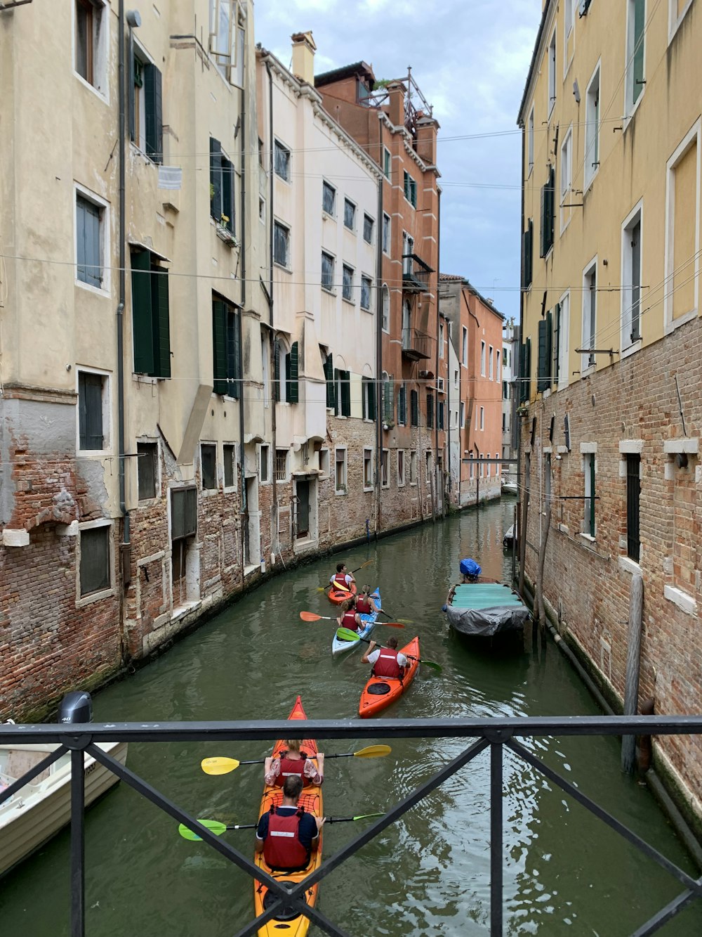 a group of small boats floating down a river next to tall buildings