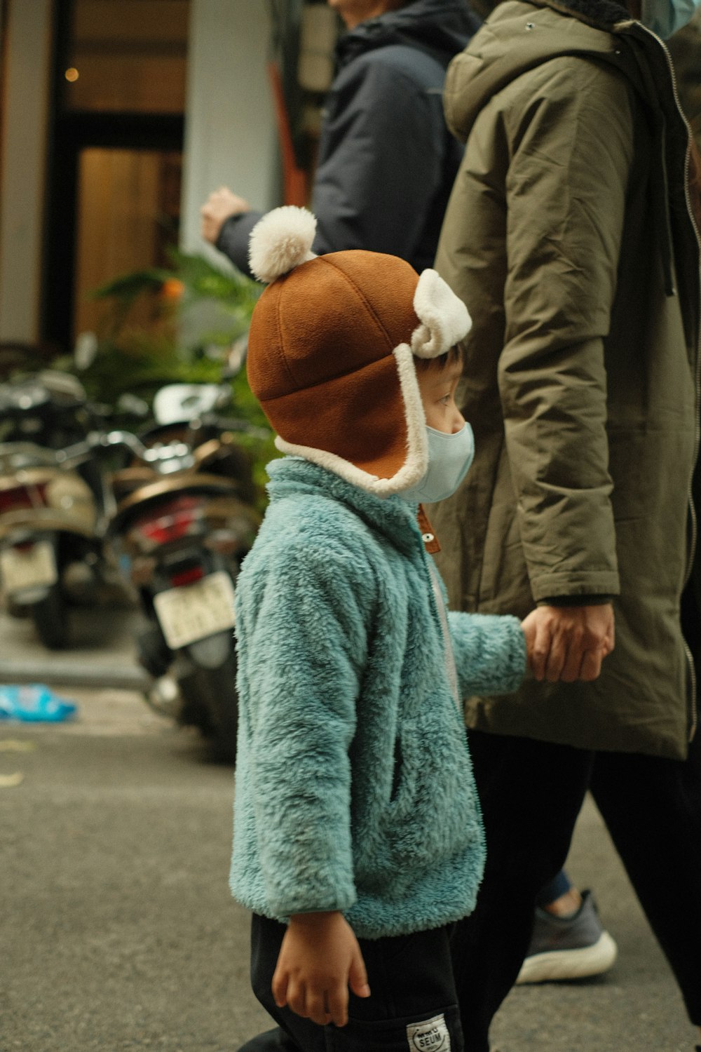 a small child wearing a face mask walking down a street