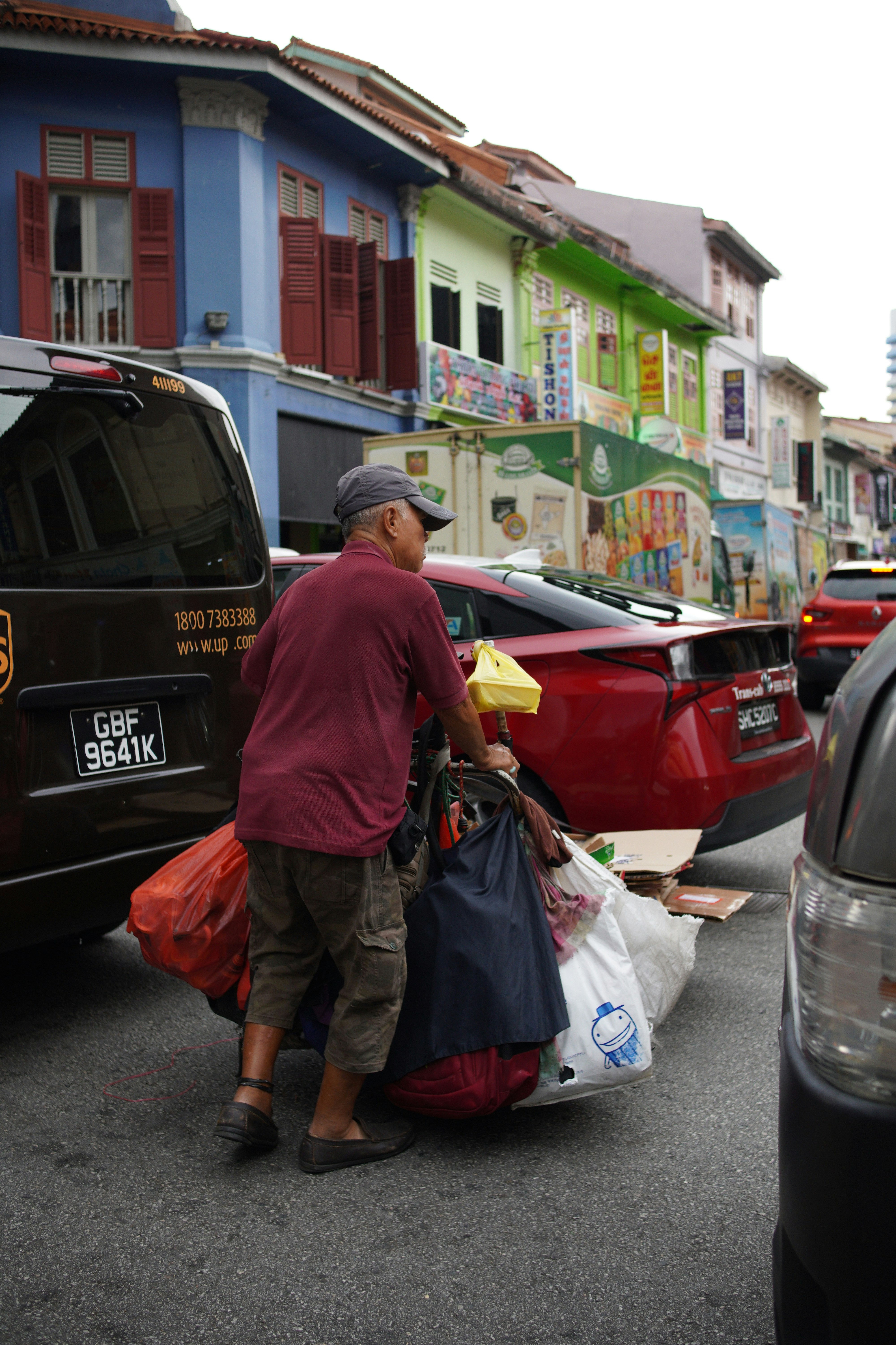 a man pushing a cart full of bags down a street