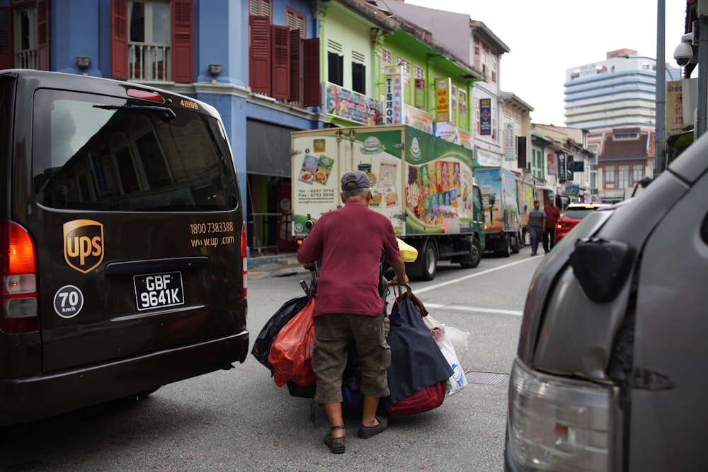 a man carrying bags of luggage down a street