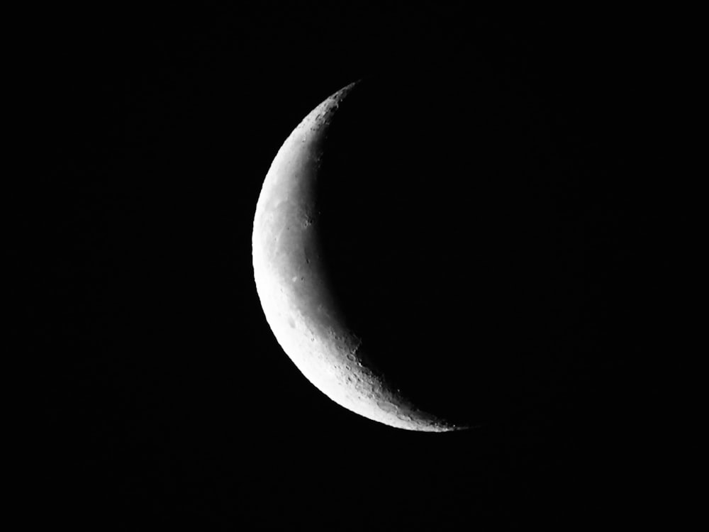 a half moon is seen in the dark sky