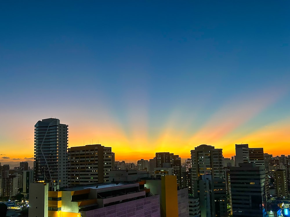 the sun is setting over a city with tall buildings