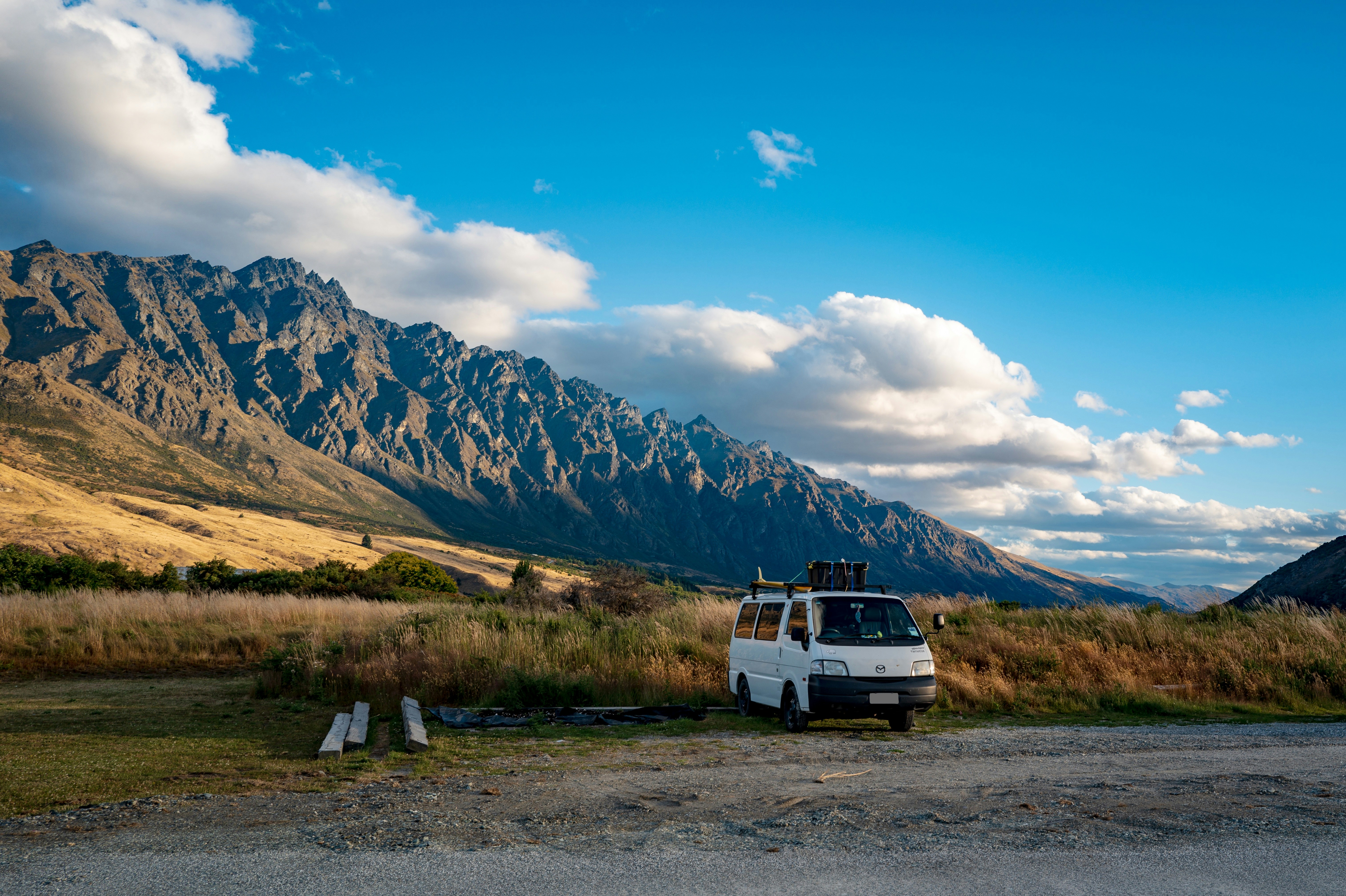a van parked on the side of a road in front of a mountain range