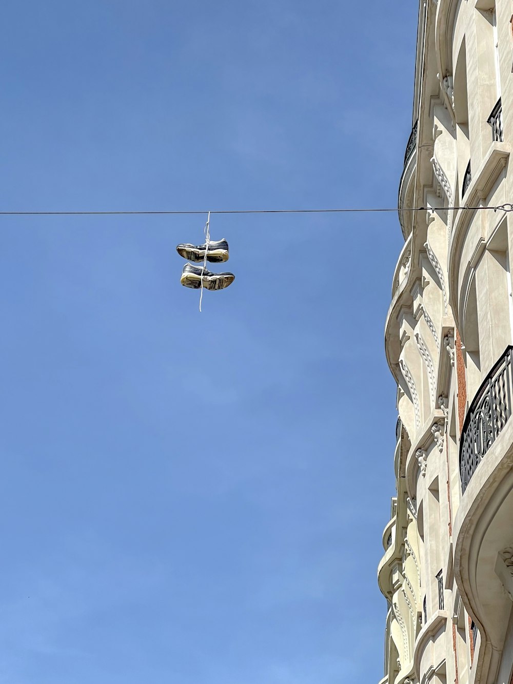 a pair of shoes hanging from a wire in front of a building