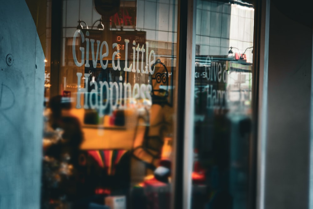 a store window with a sign that says give a little happiness