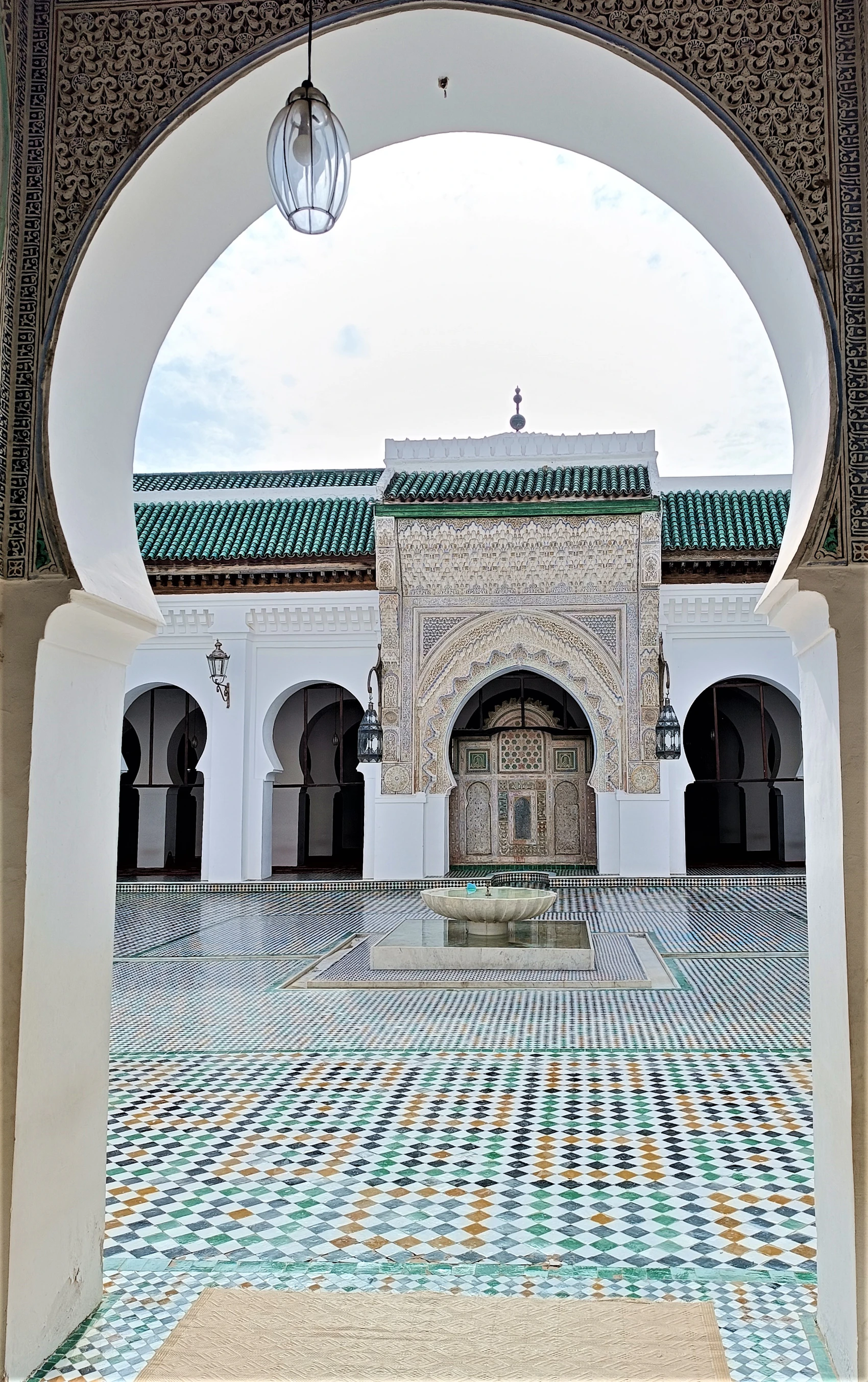 An ornate tiled courtyard and fountain inside a historic Fès madrasa