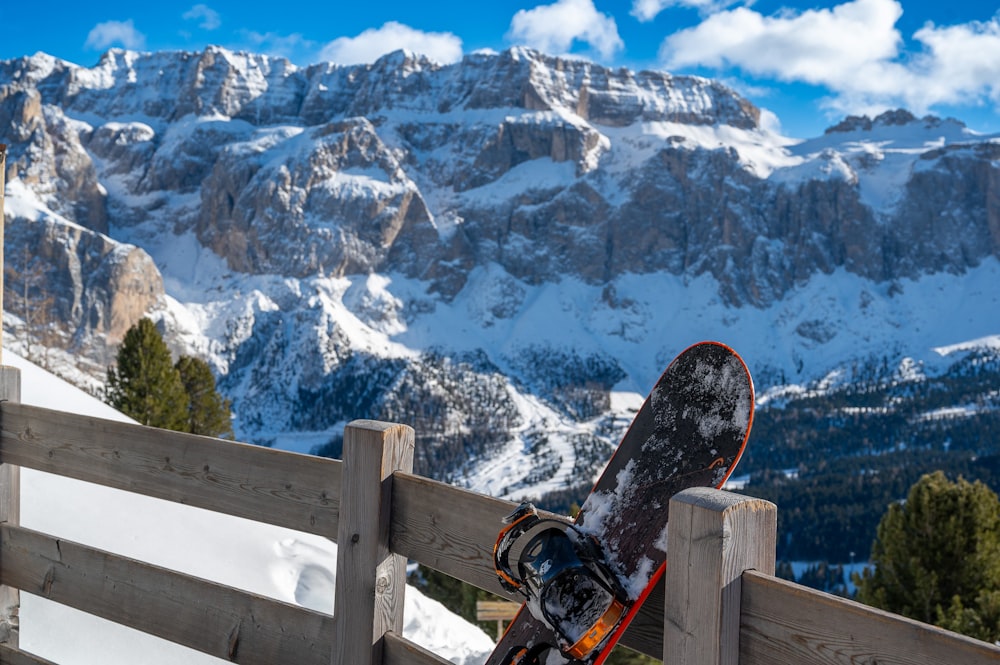 a snowboard leaning against a fence with mountains in the background