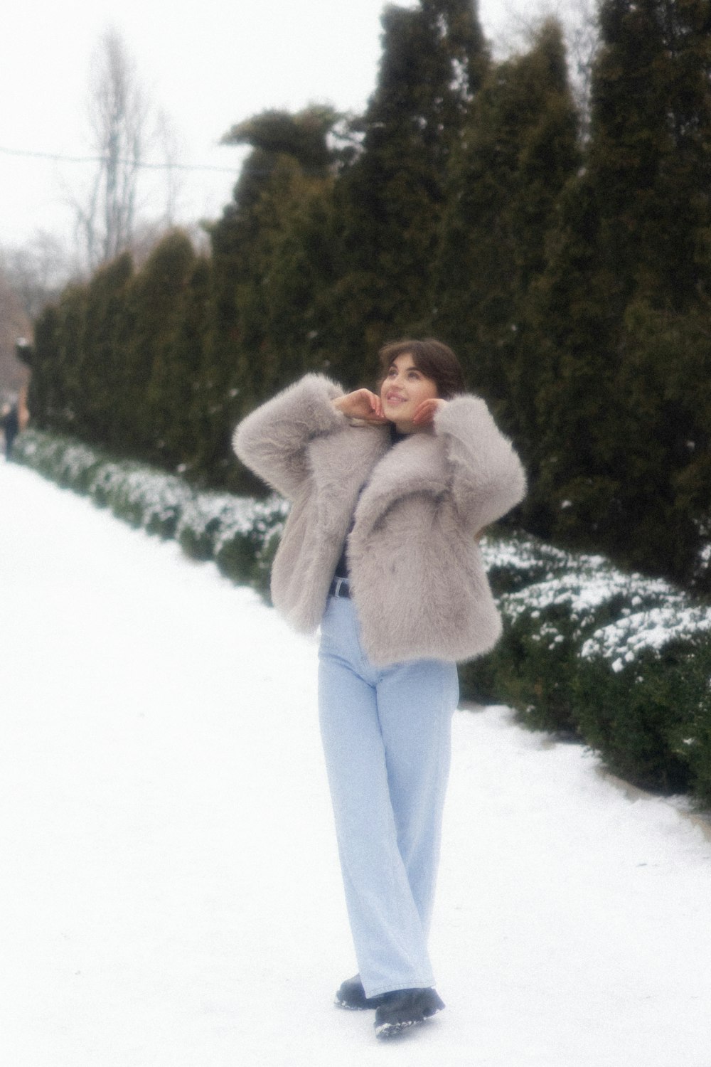 a woman standing in the snow wearing a fur coat