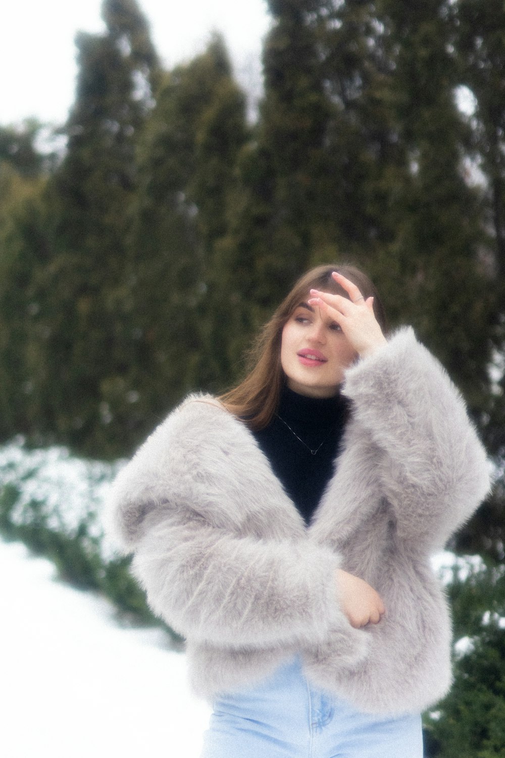 a woman standing in the snow with her hand on her face