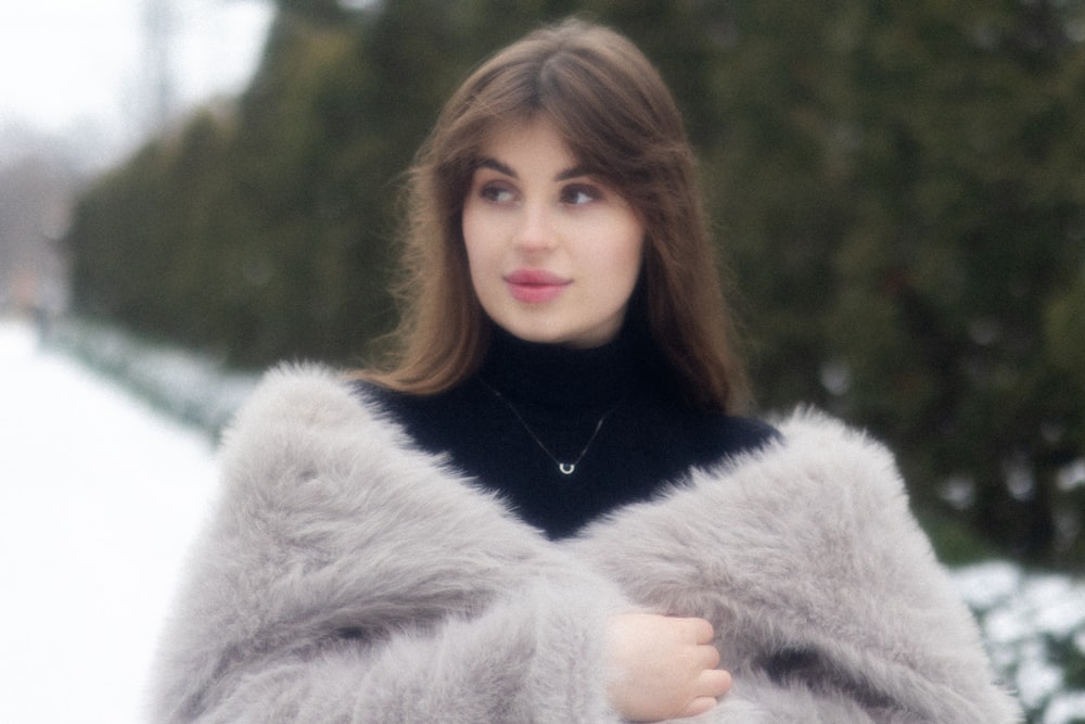 a woman in a fur coat standing in the snow