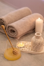 a table topped with candles and towels next to a jar of honey