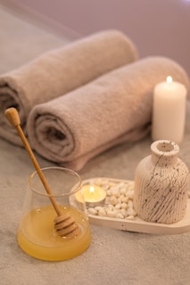 a table topped with candles and towels next to a jar of honey