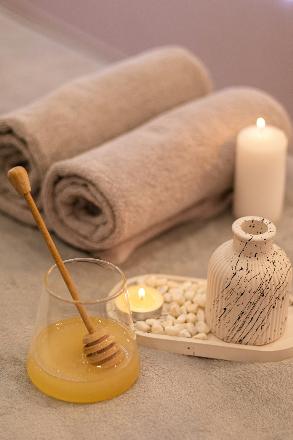 a table topped with candles and towels next to a jar of honey