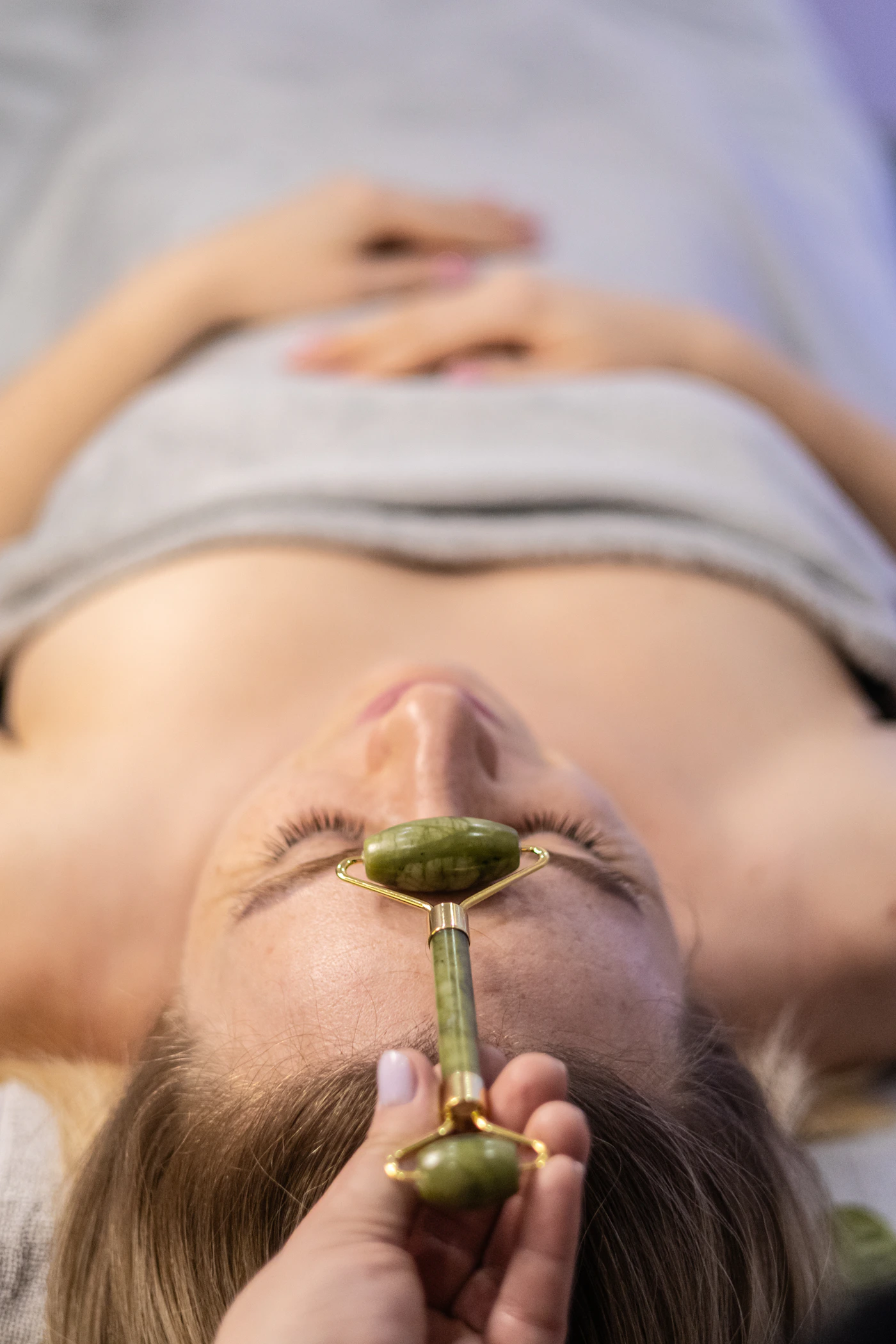 Woman receiving a facial treatment with a handheld wellness device