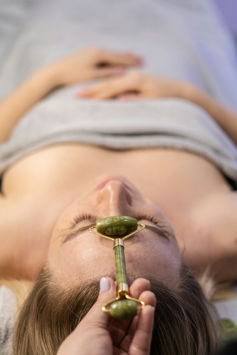 a woman getting a facial massage with a green device