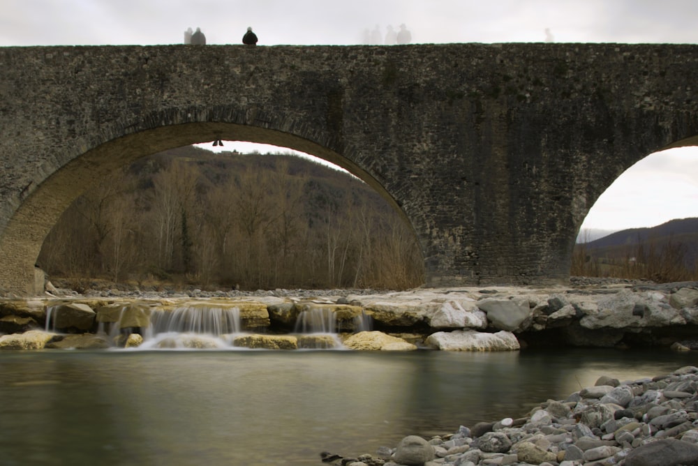 a stone bridge over a river with a waterfall