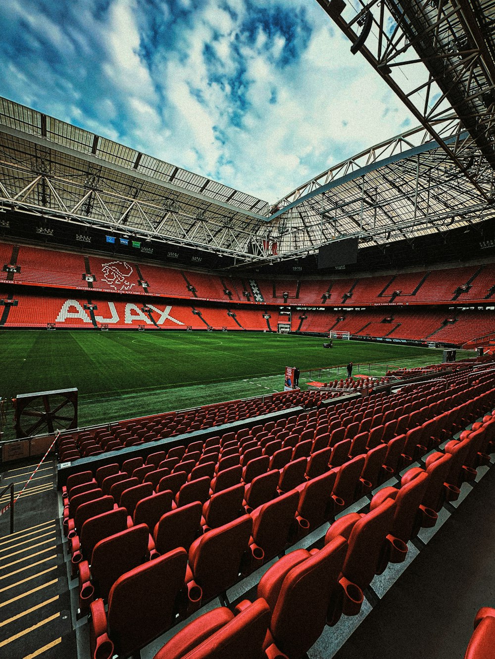 a stadium filled with red seats under a cloudy sky