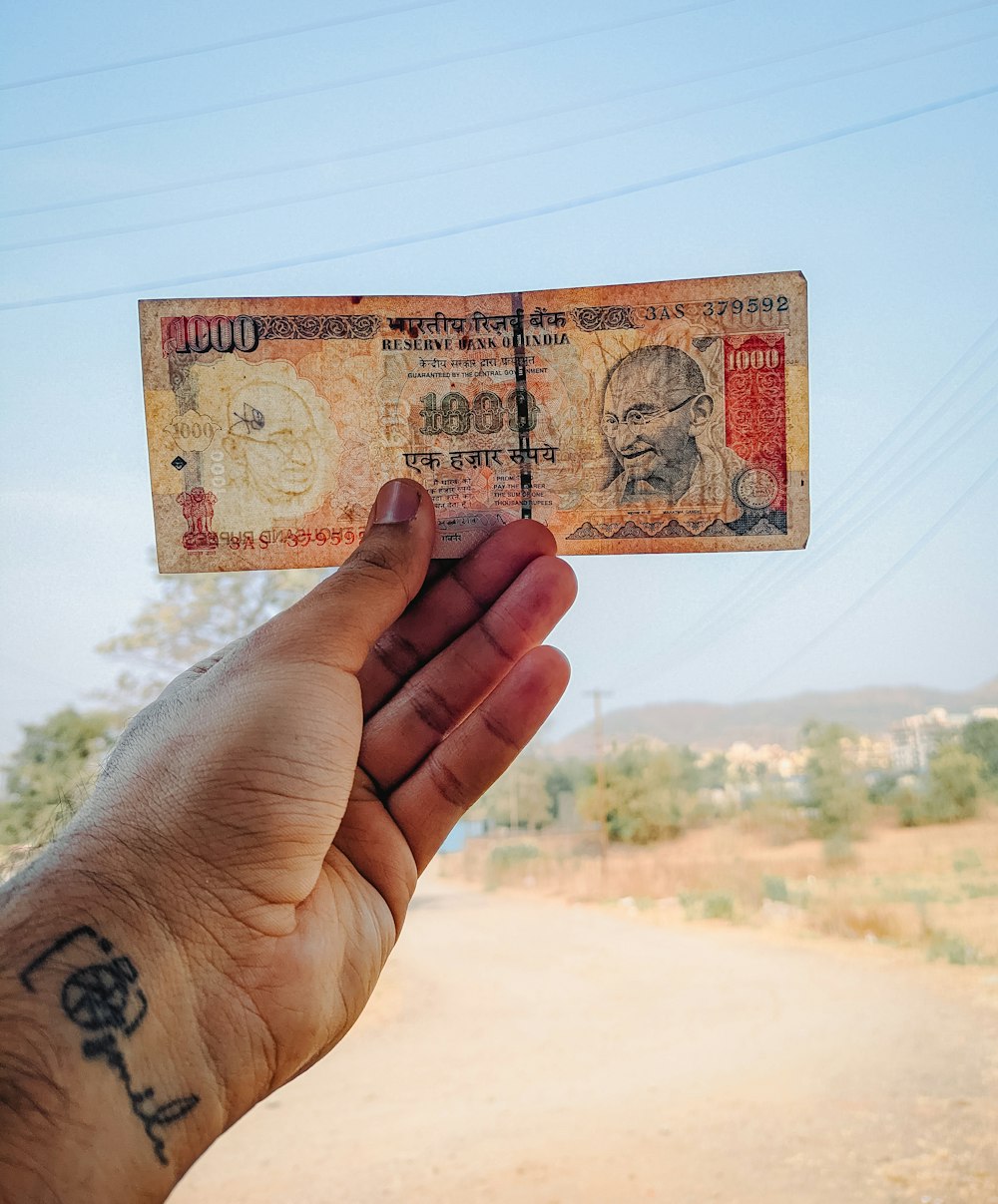 a hand holding a piece of paper with a picture of a man's face