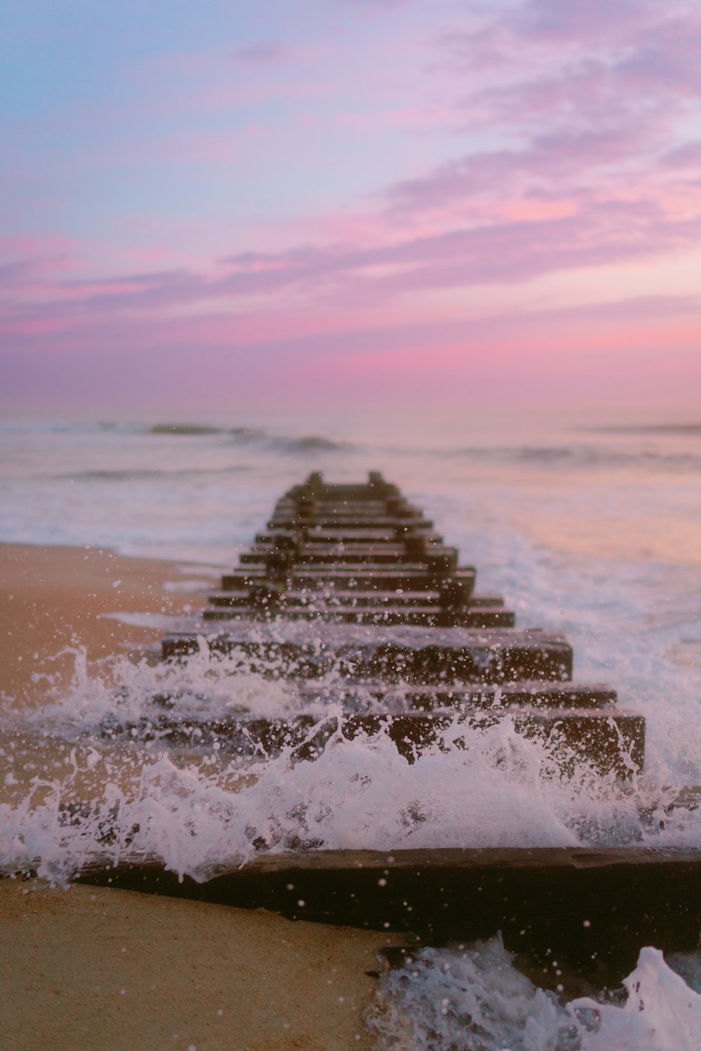 a row of wooden benches sitting on top of a sandy beach