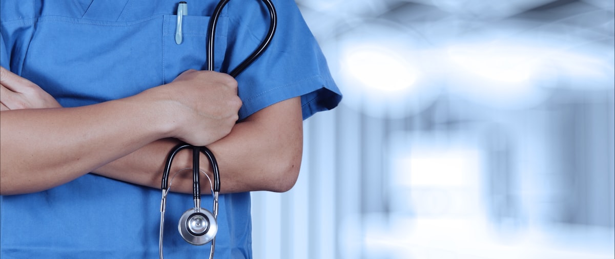Psychiatric nurse in scrubs using AI documentation tools during a patient shift in 2026
