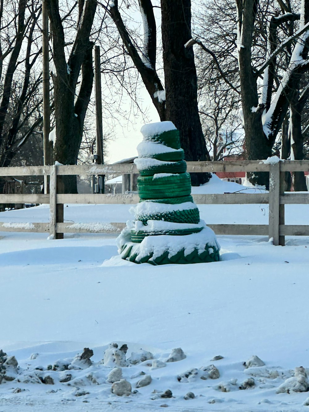 a green fire hydrant covered in snow next to trees