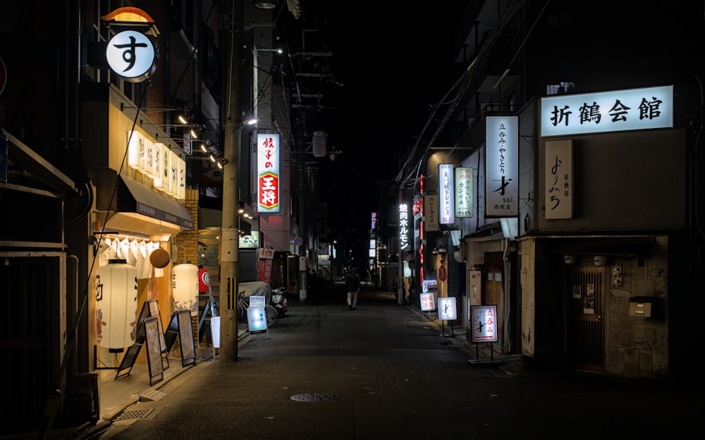 a dark alley with signs and lights on the buildings