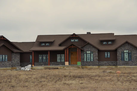 a large brown house sitting on top of a dry grass field