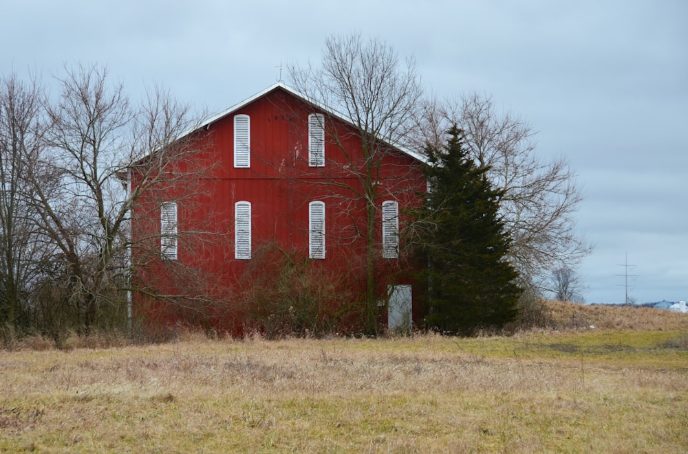 an old red barn sits in a field