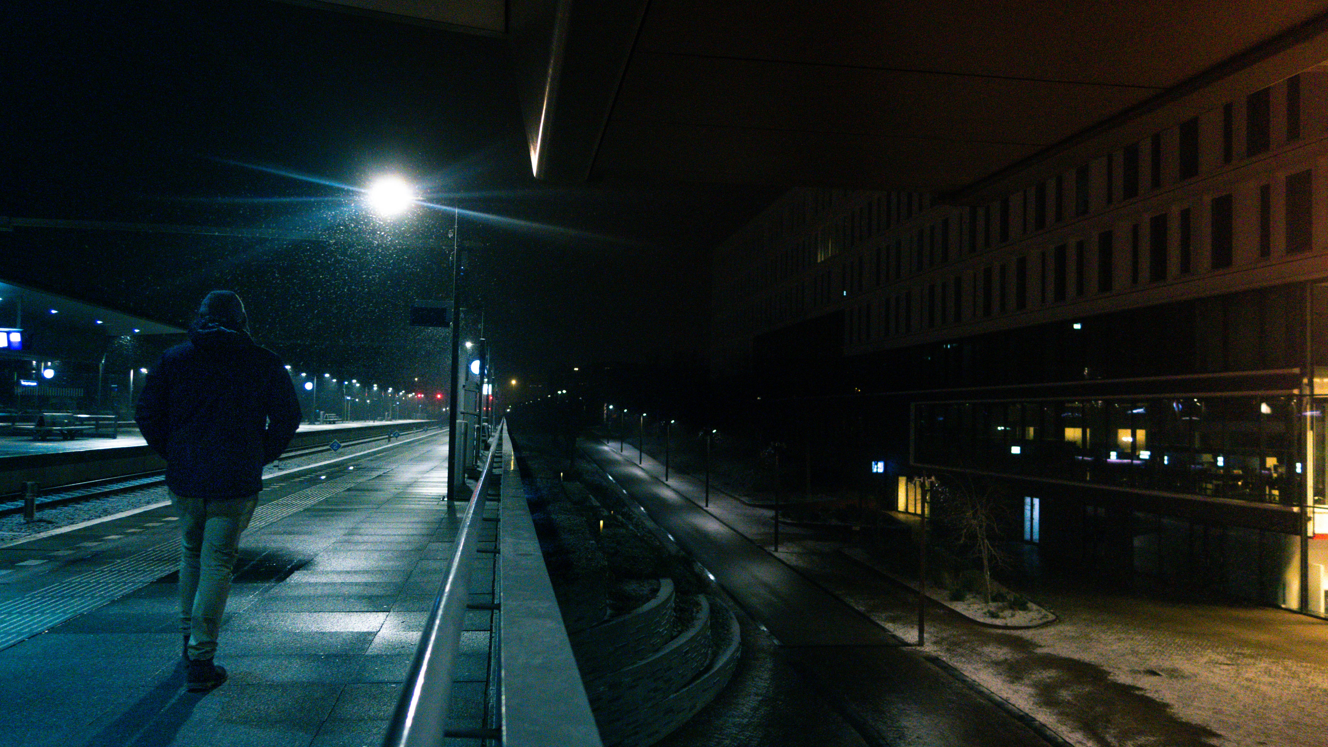 a person walking down a sidewalk at night
