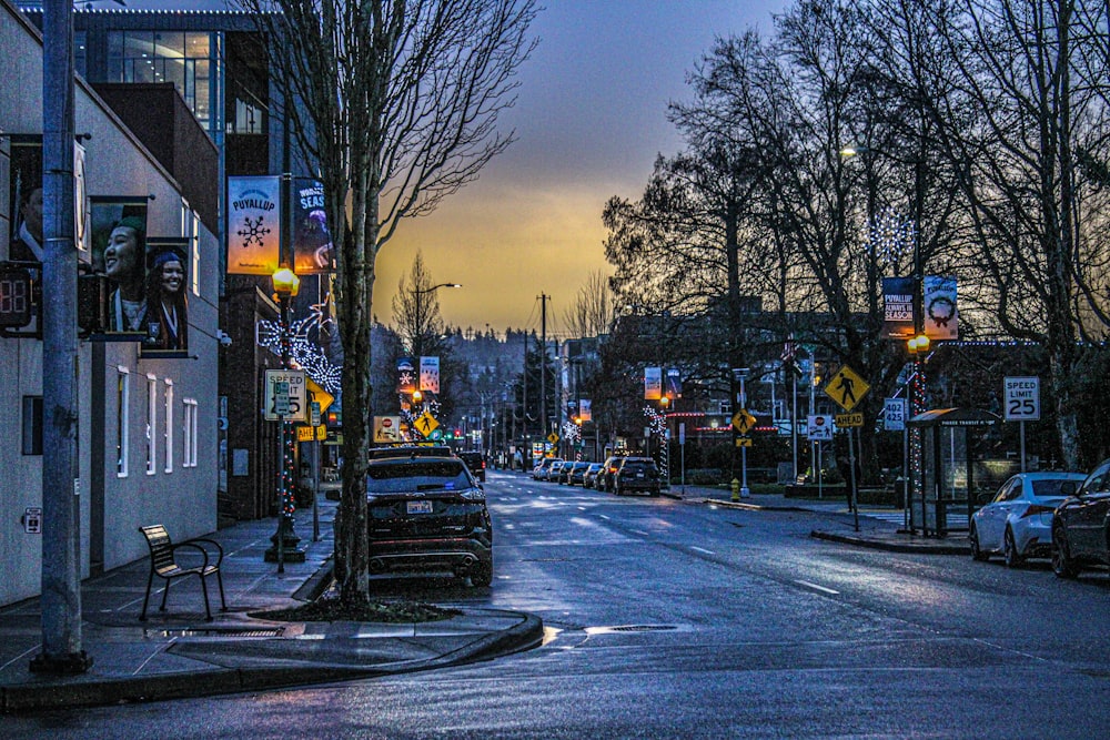a city street at dusk with cars parked on the side of the road