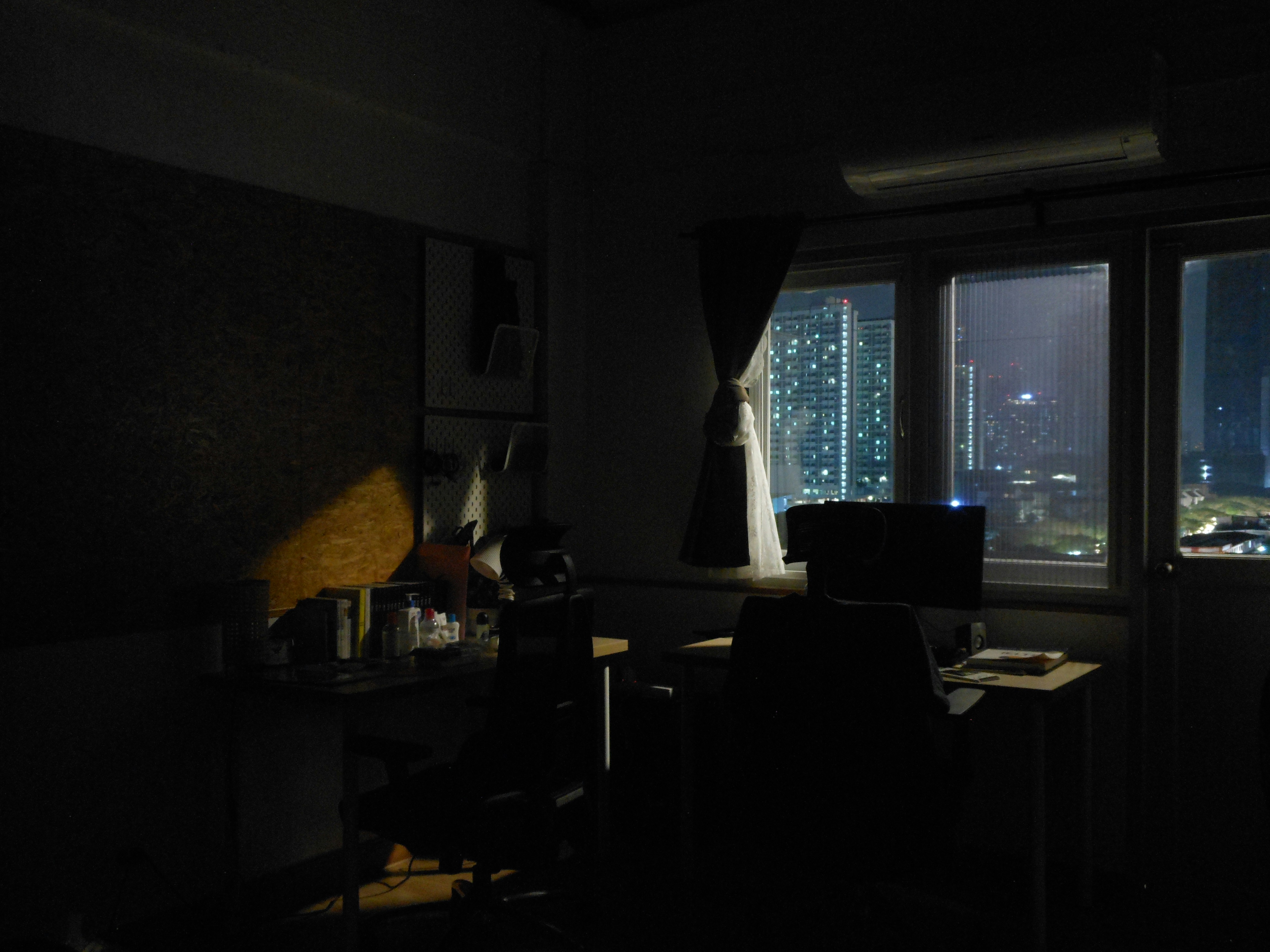 a dark room with a desk and a window