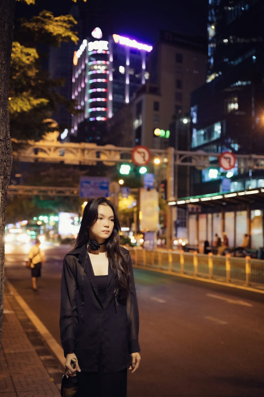 a woman standing on the side of a road at night