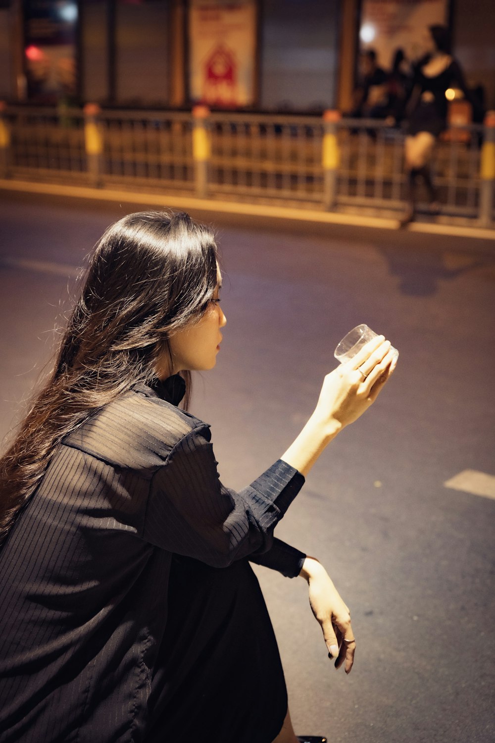 a woman sitting on the ground holding a cup of coffee