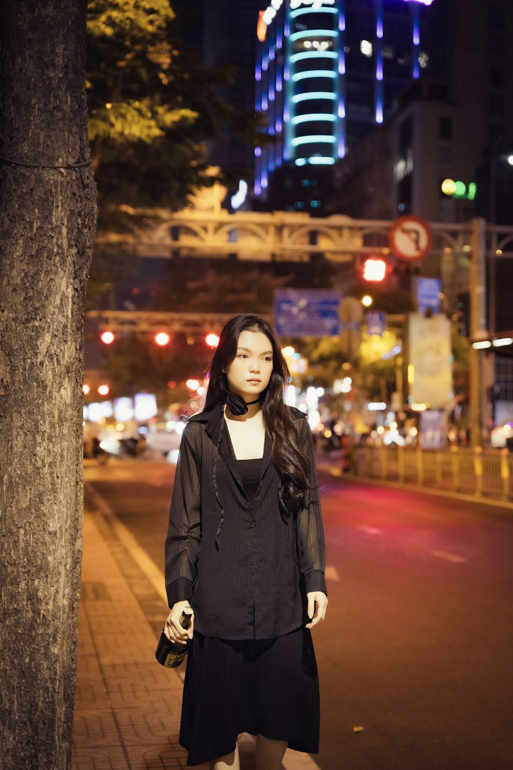 a woman standing on the side of a street at night