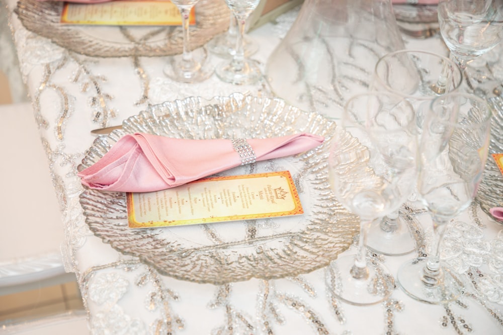 a pink napkin on a glass plate on a table