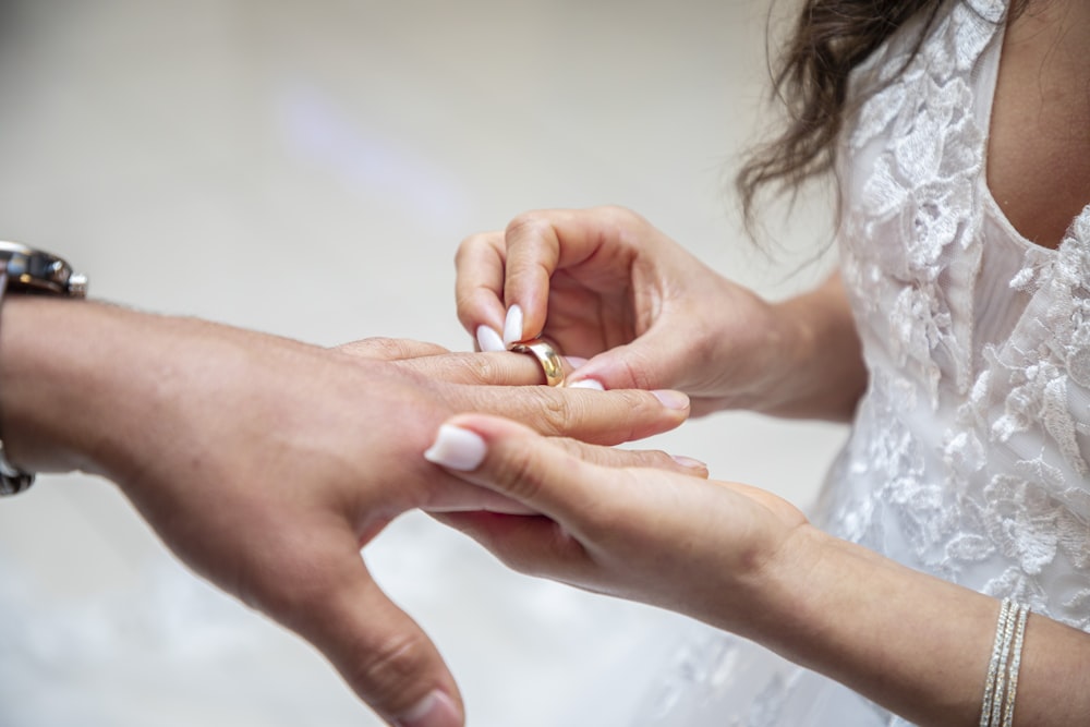 a bride putting a wedding ring on a groom's finger