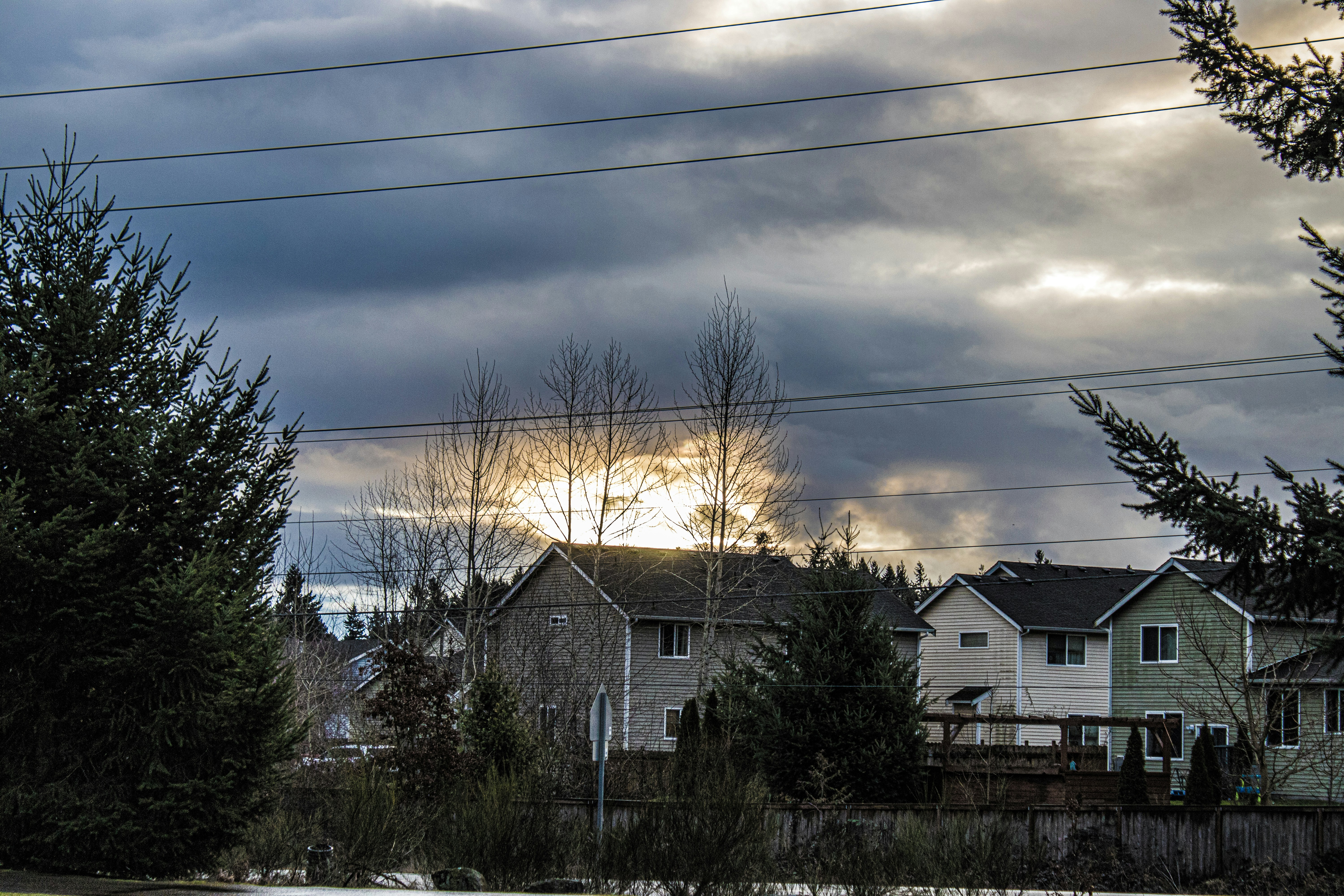 Sun breaking through heavy storm clouds over a row of houses