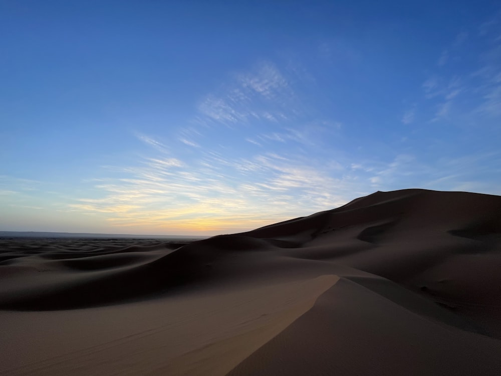 the sun is setting over the sand dunes